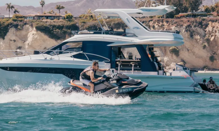 A jet ski running alongside Andiamo below the cliffs
